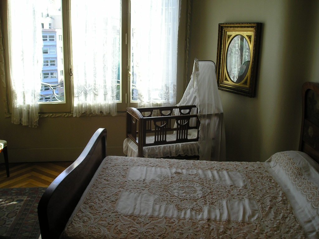 the view of a bedroom with a crib, picture frame and window