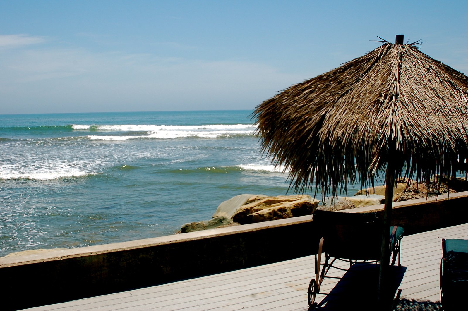 an umbrella and chair overlooking a beach that's on the water