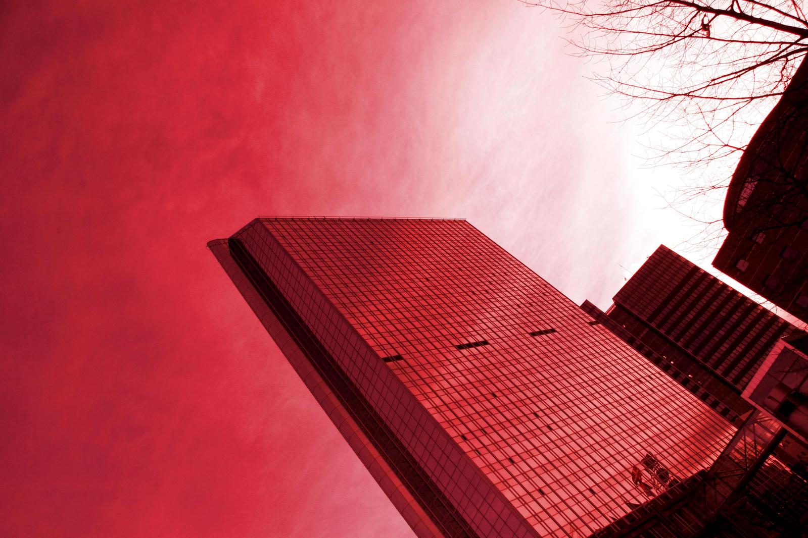 a tall red building with trees in the foreground
