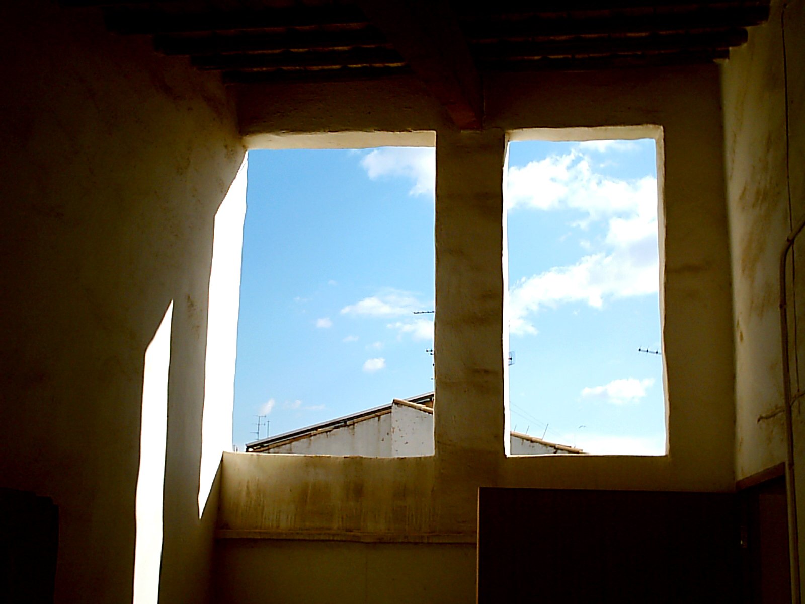 a shadow of a building on the wall behind two windows