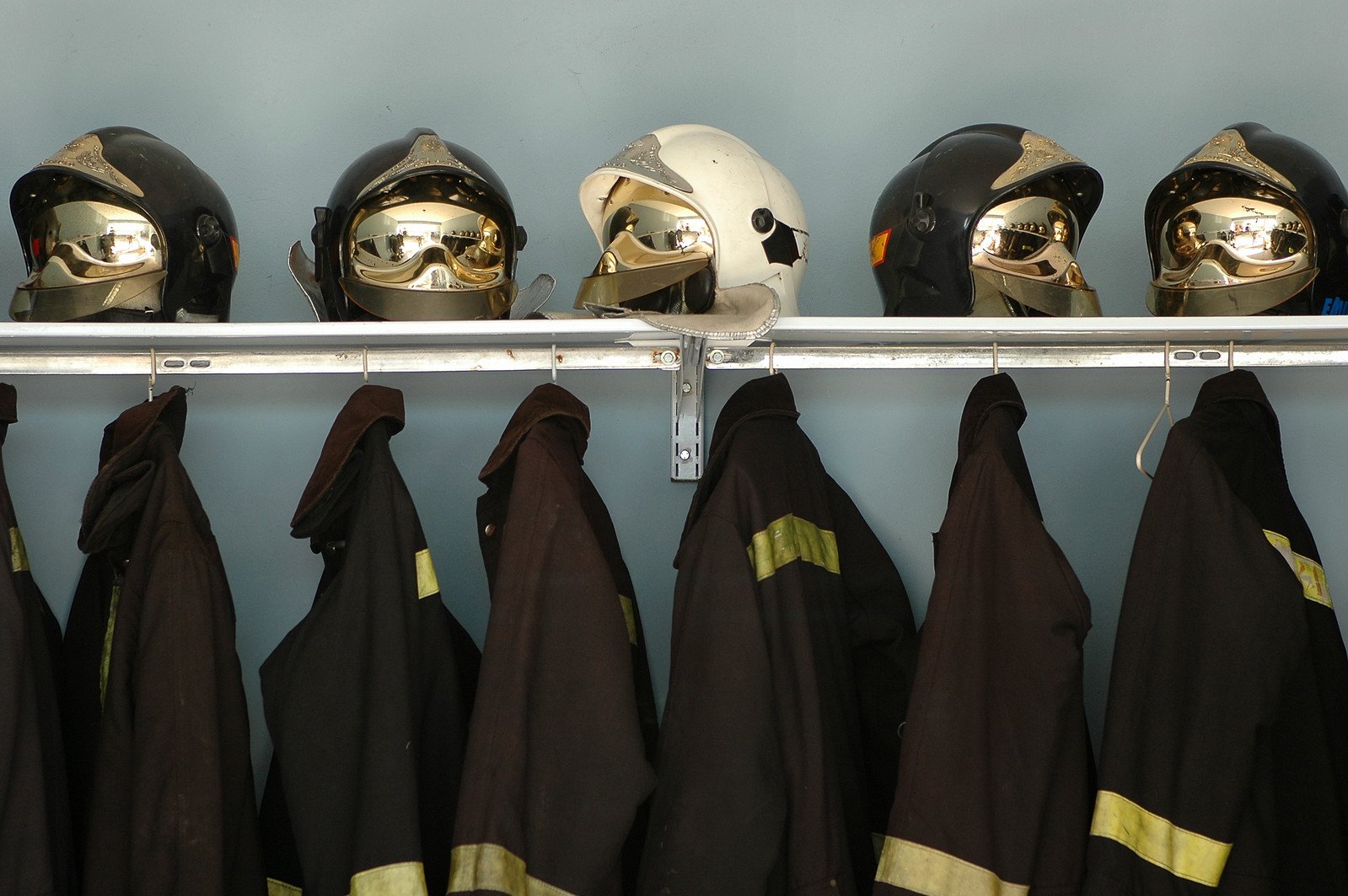 several different types of helmets hang on a metal rail
