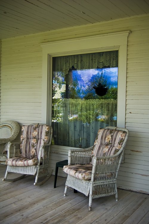 two chairs sitting on a porch next to a glass door