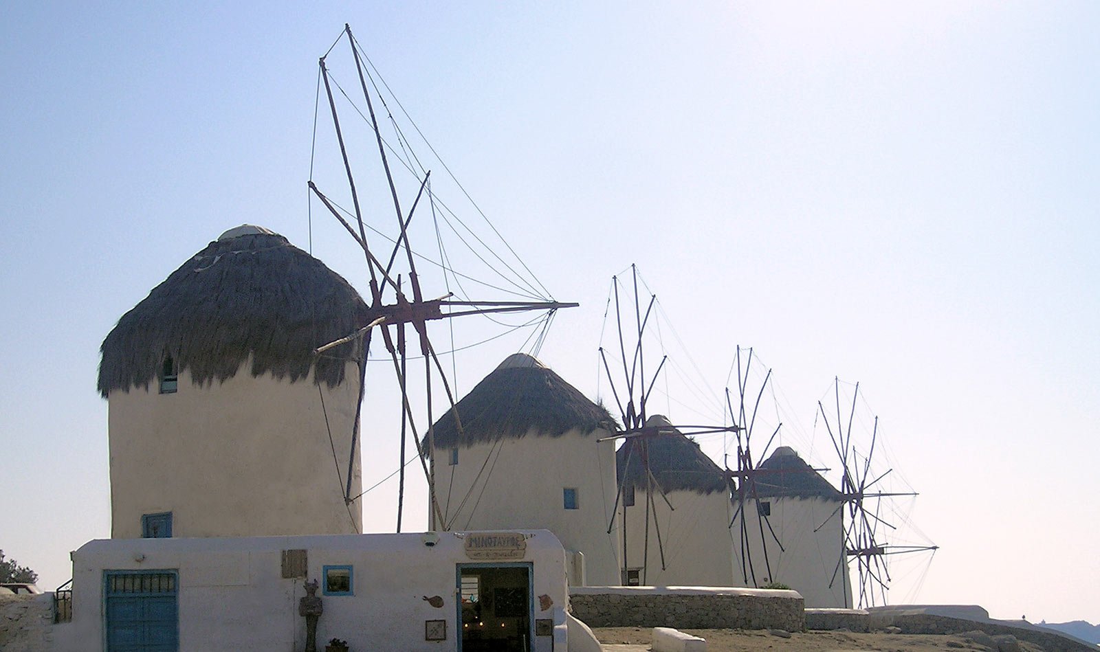 a number of windmills on a hill near a body of water