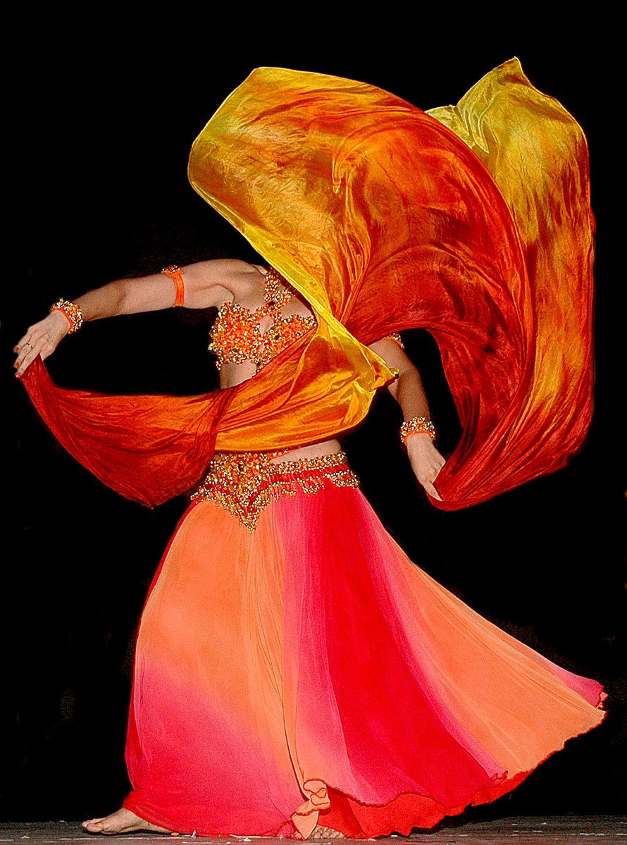 a woman wearing a long orange and yellow gown with a red flowing scarf