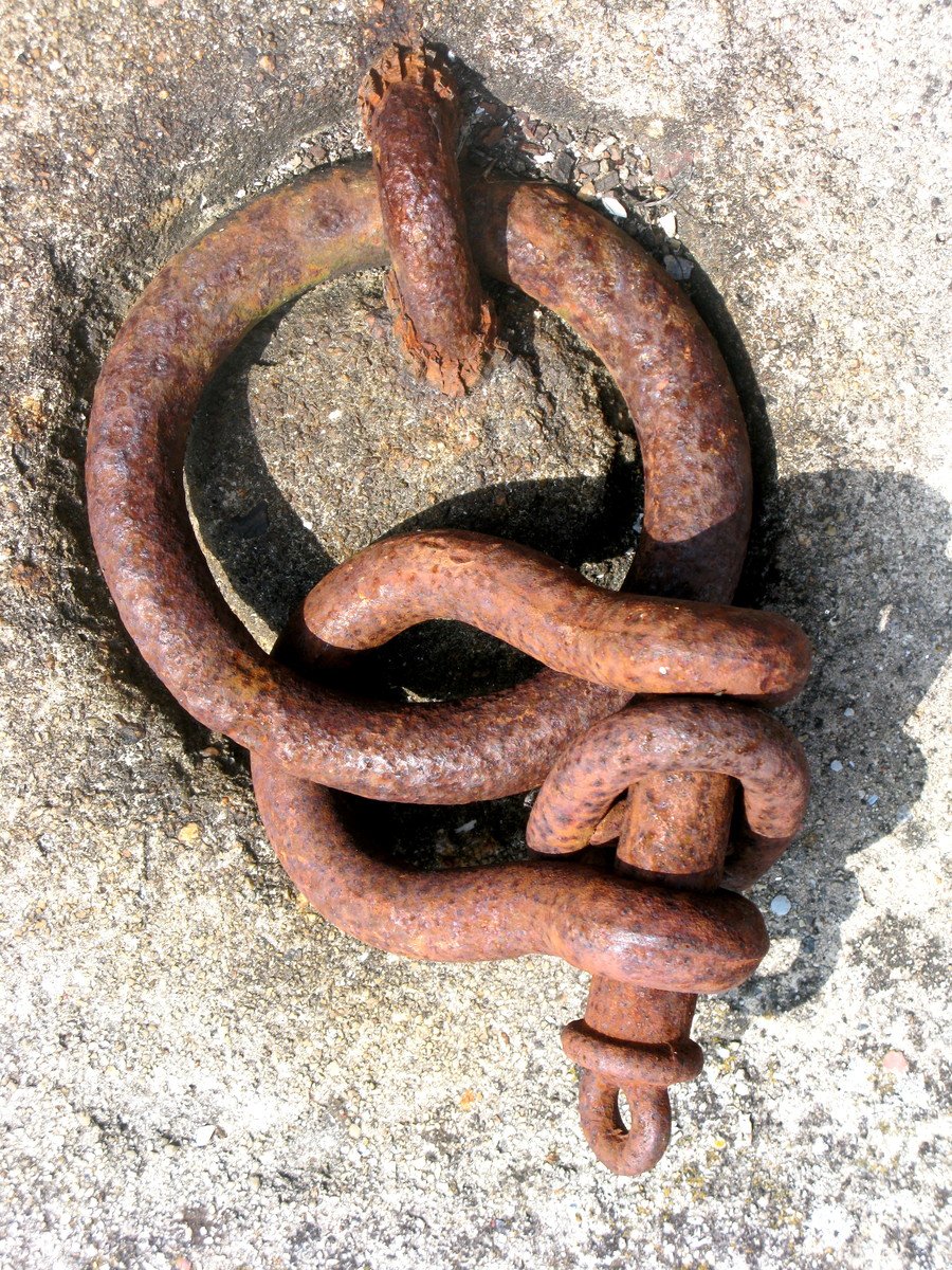 a rusty rusted chain on a curb in the daytime