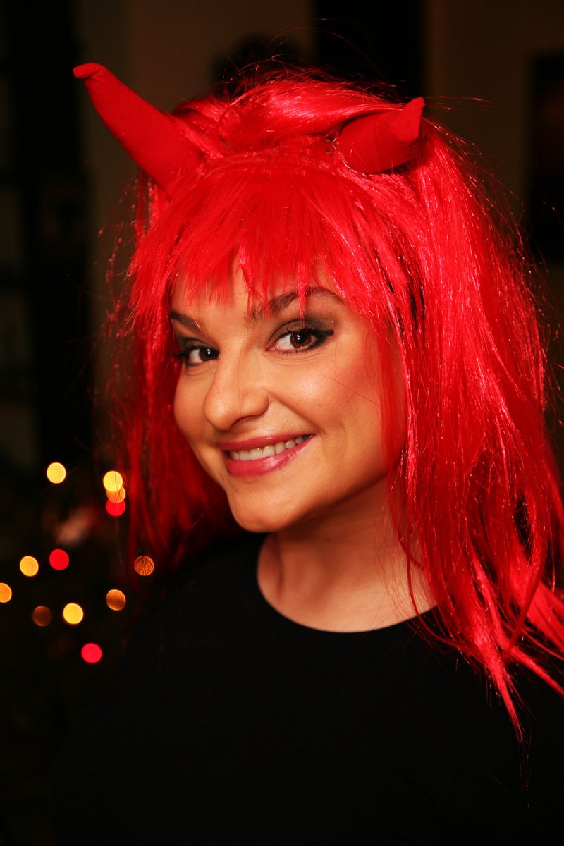 the woman has red hair and is wearing devil horns