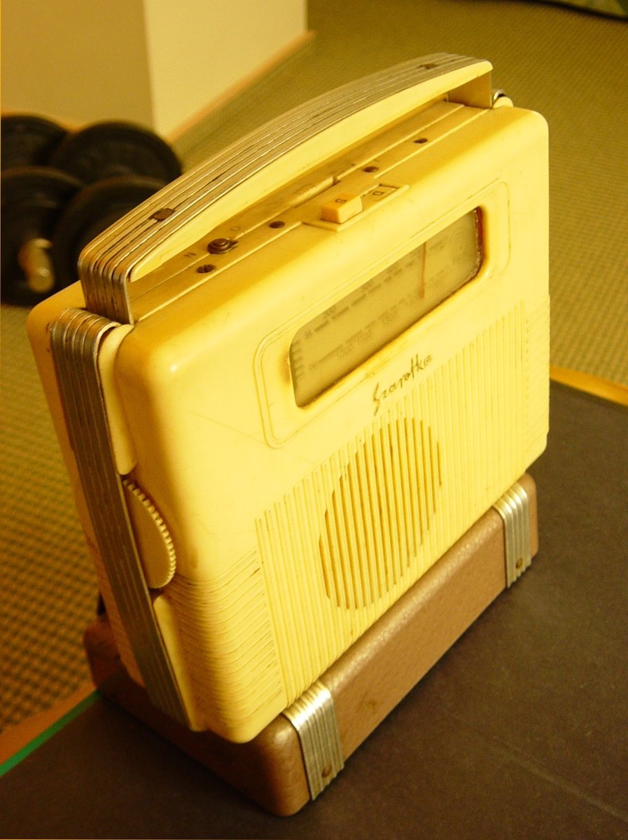 an old yellow radio sitting on top of a wooden table