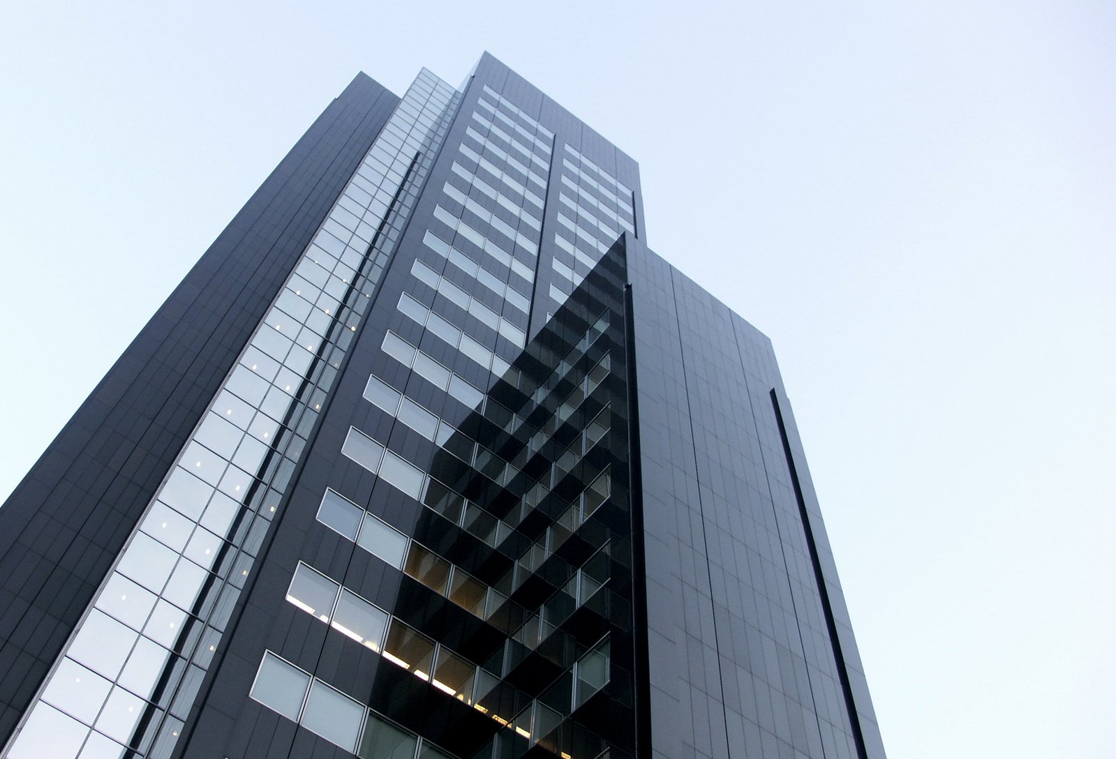 a tall building with glass windows and a sky background