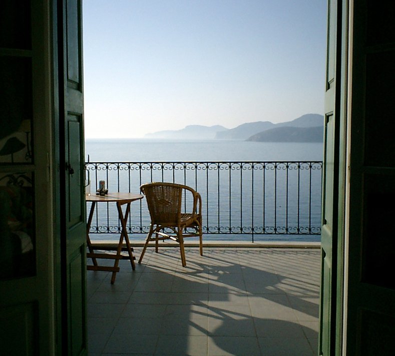 a table and chair are on the outside patio near the ocean