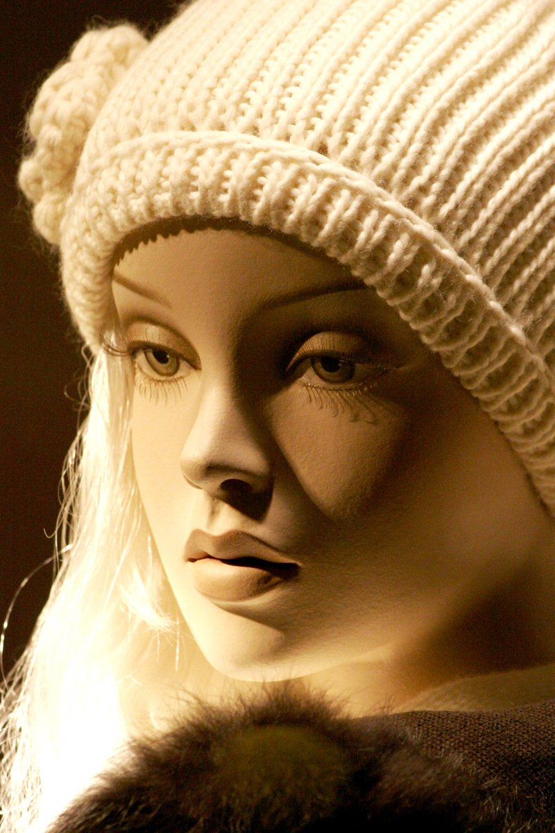 a close up of a female mannequin head in a white hat and black jacket