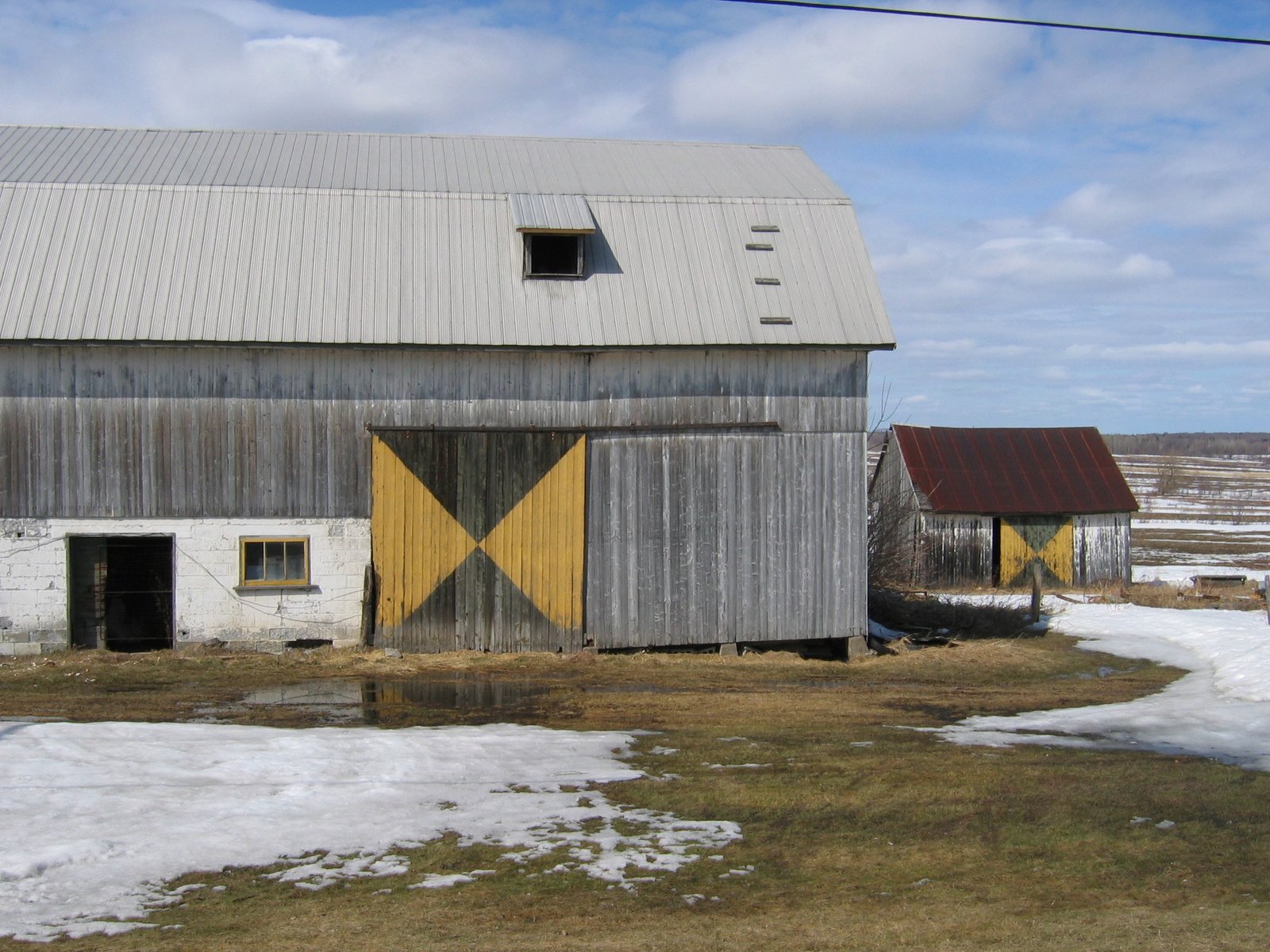 two barns on the side of a snowy field