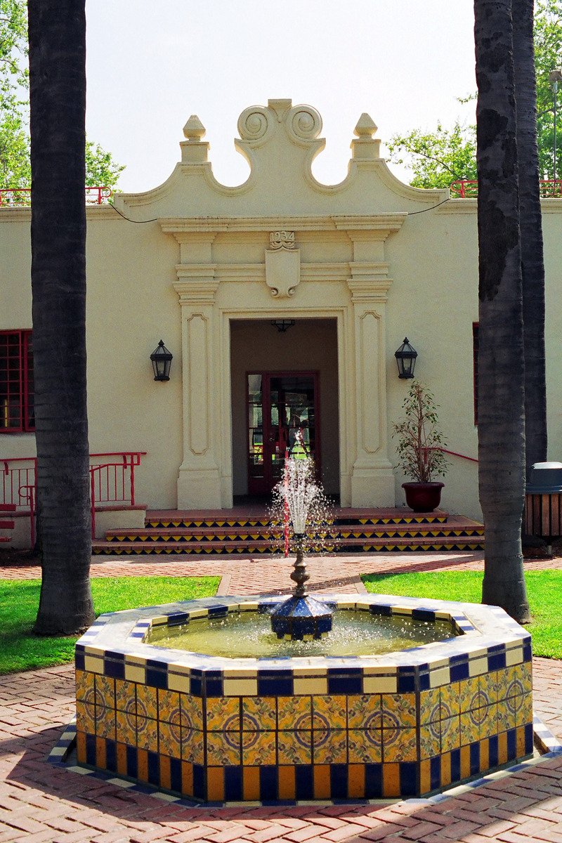a fountain in front of a building next to palm trees