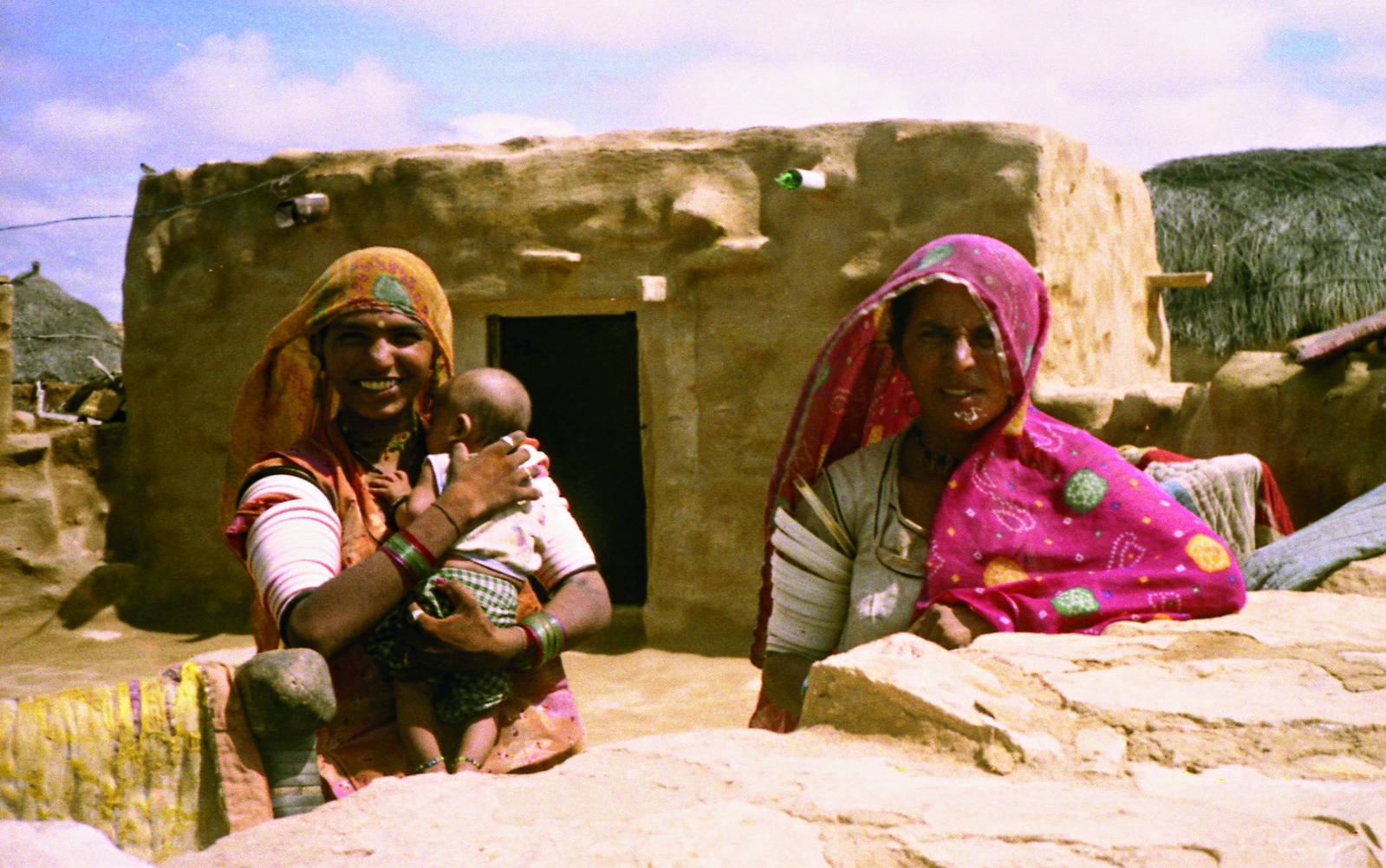 two women in their native homes with a baby