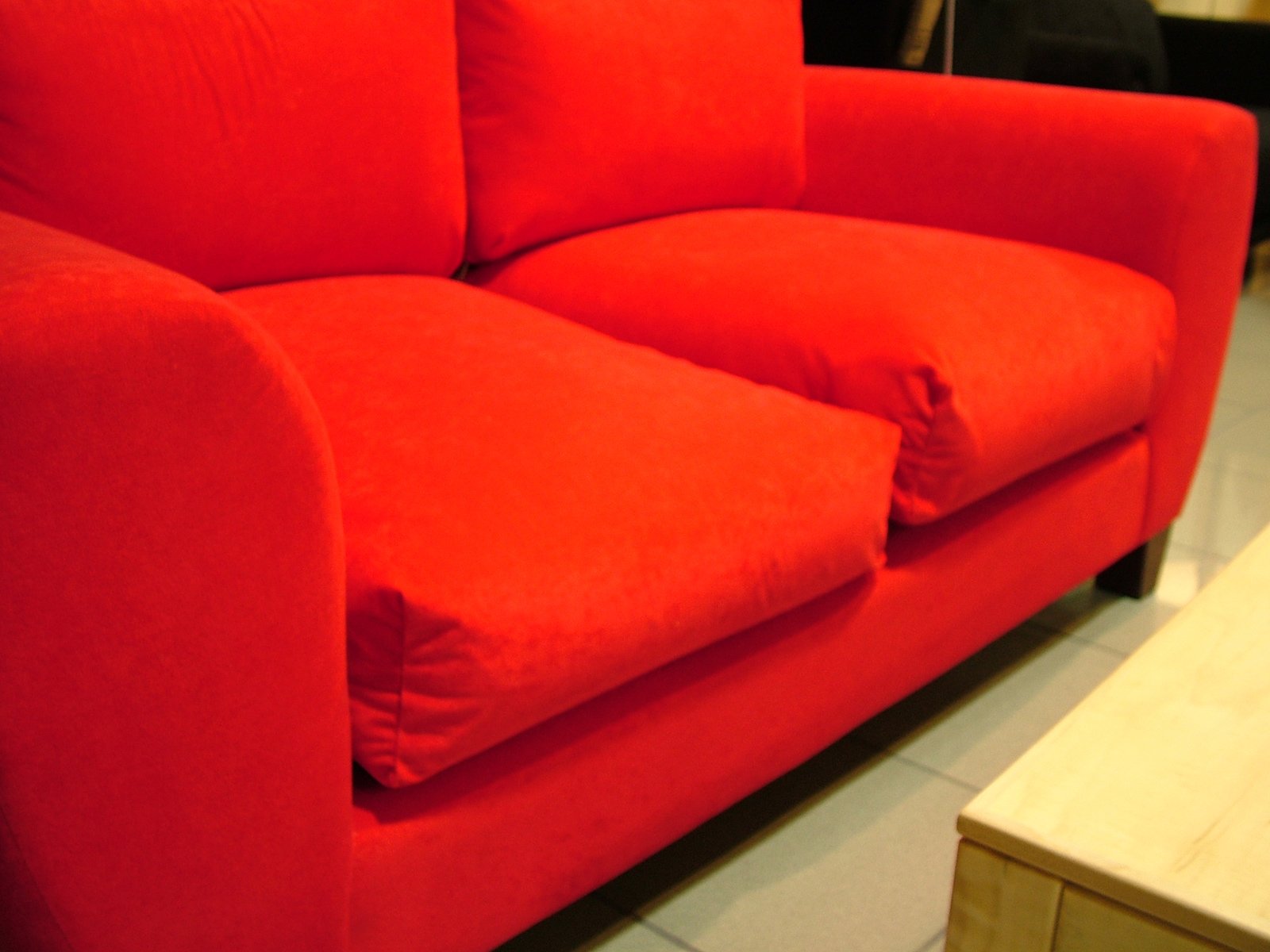 an orange couch with pillows, sits next to a table