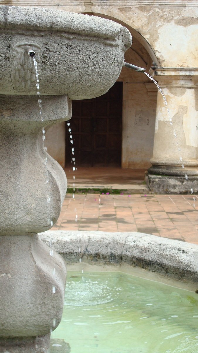 a stone water fountain with the water pouring out of it