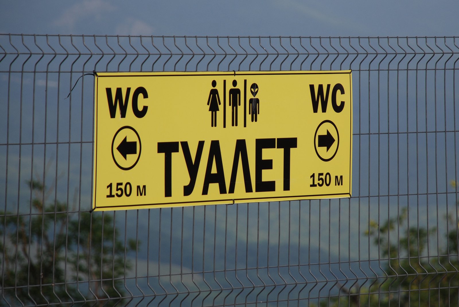 a sign in front of a metal fence reading the direction to a w and tayet