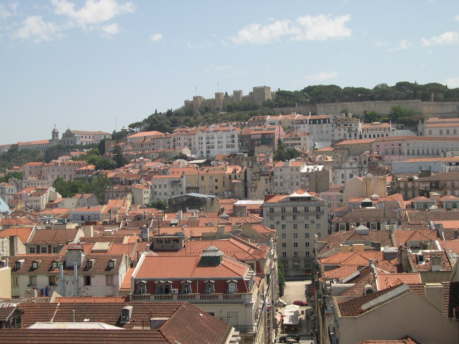 large buildings and roofs in the city below a hill