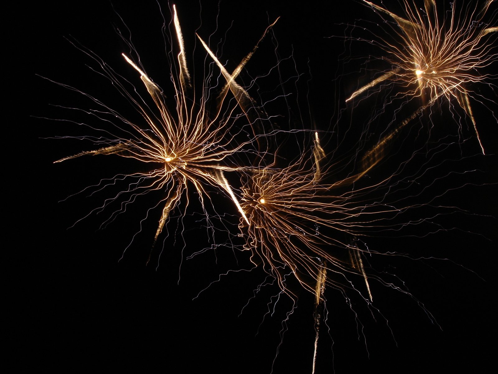three fireworks are seen in the sky with black background