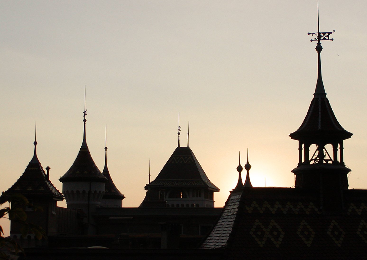 a castle with turrets and spires is silhouetted against the sky