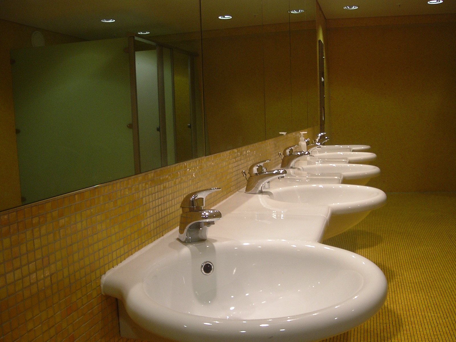 a long row of sinks with tiled wall behind them