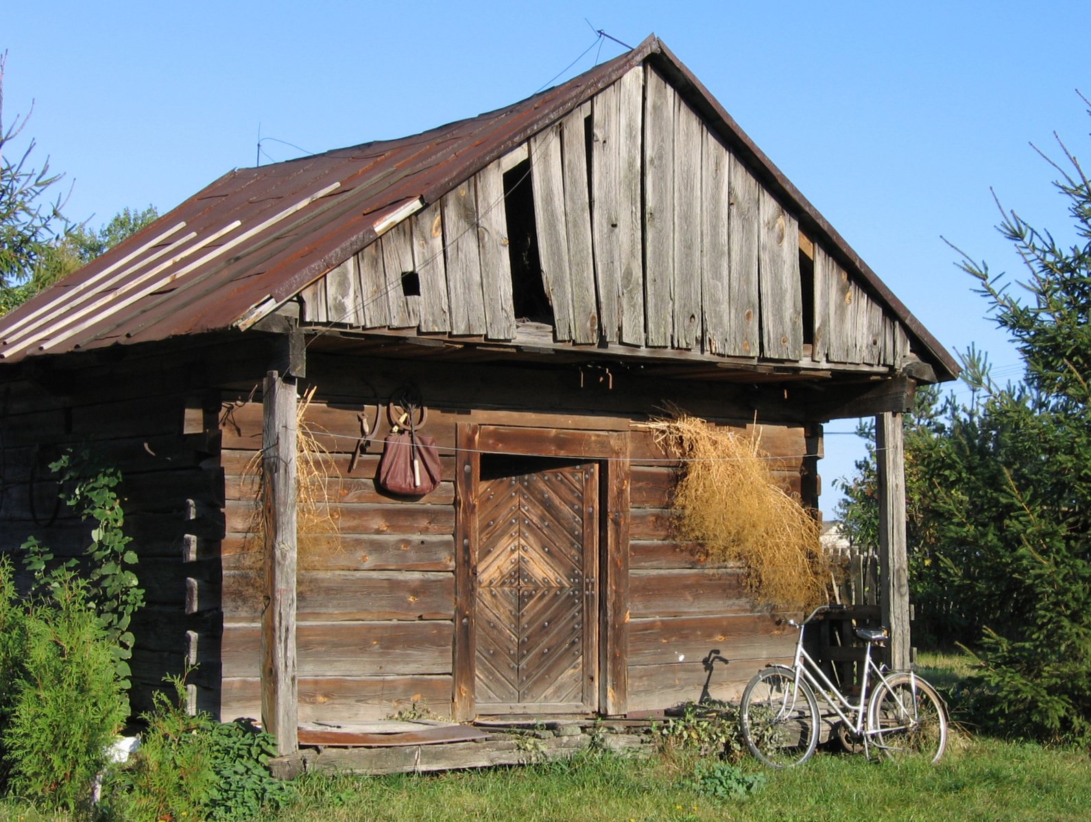 an old shed with an abandoned bicycle next to it
