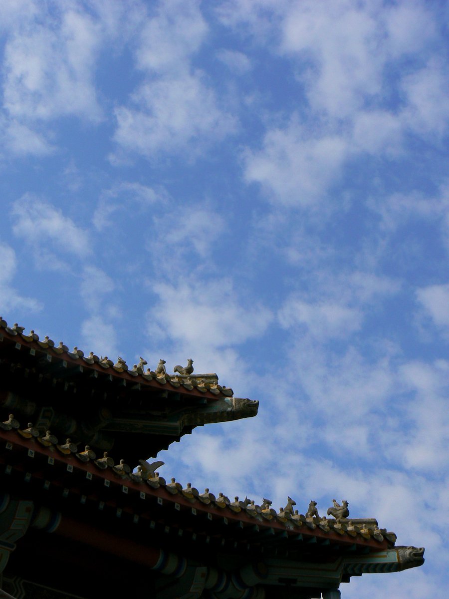 an oriental style building with an arrow pointing upward on a cloudy day