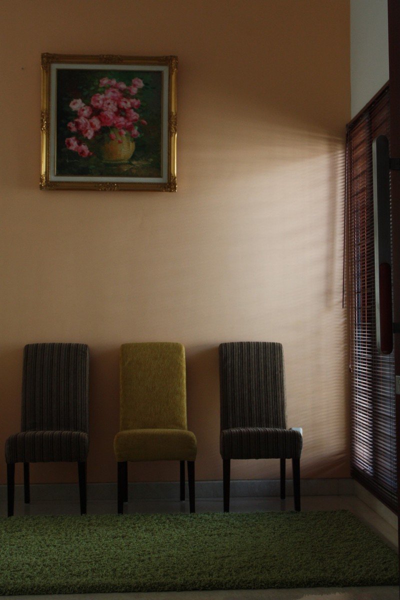 three chairs next to a flower painting and a green rug