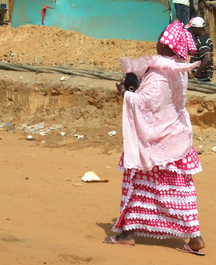 a woman walking across a dirty area carrying an object