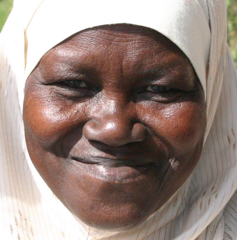 a woman with a white scarf is smiling at the camera