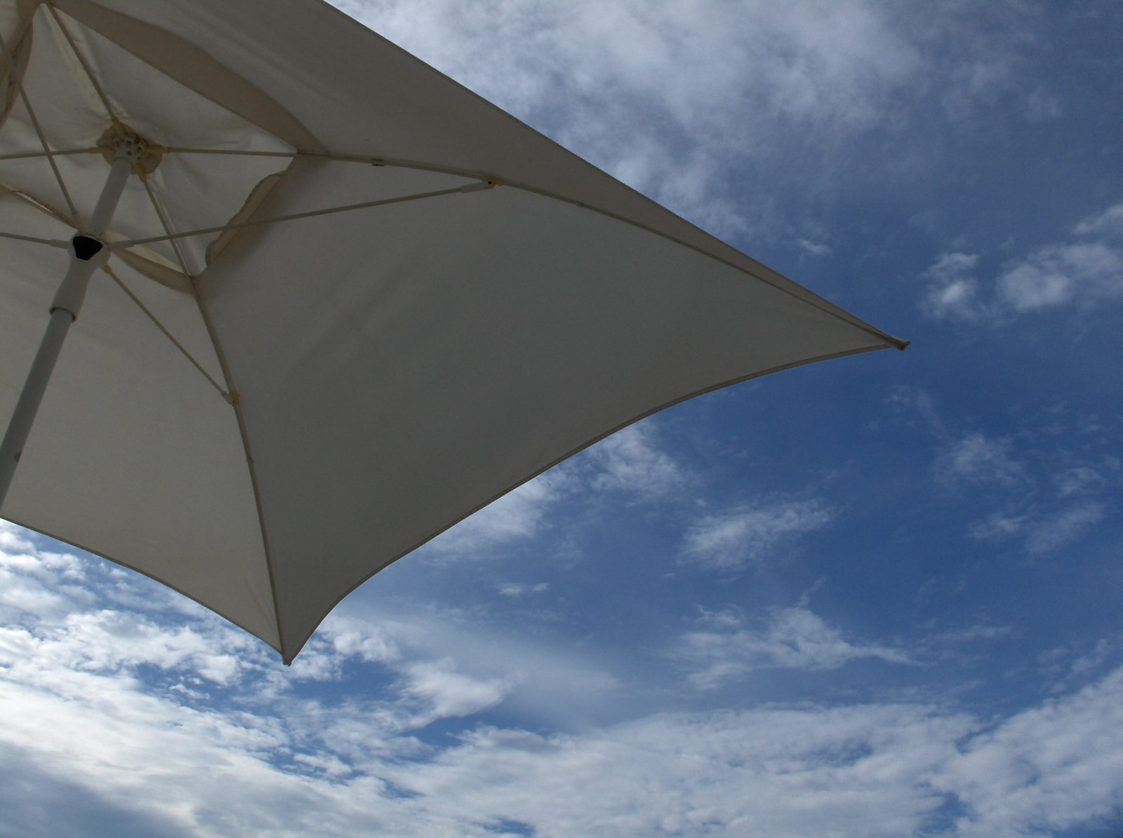 an umbrella up against the blue sky and white clouds