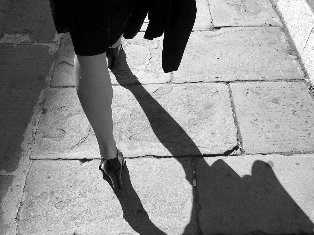 a woman is walking with her  apart on the sidewalk