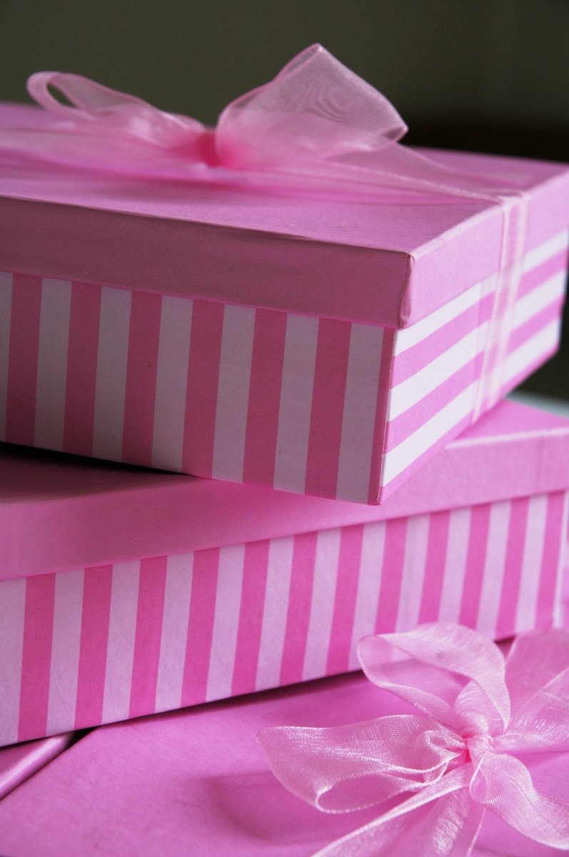 pink boxes with bows are stacked on top of each other