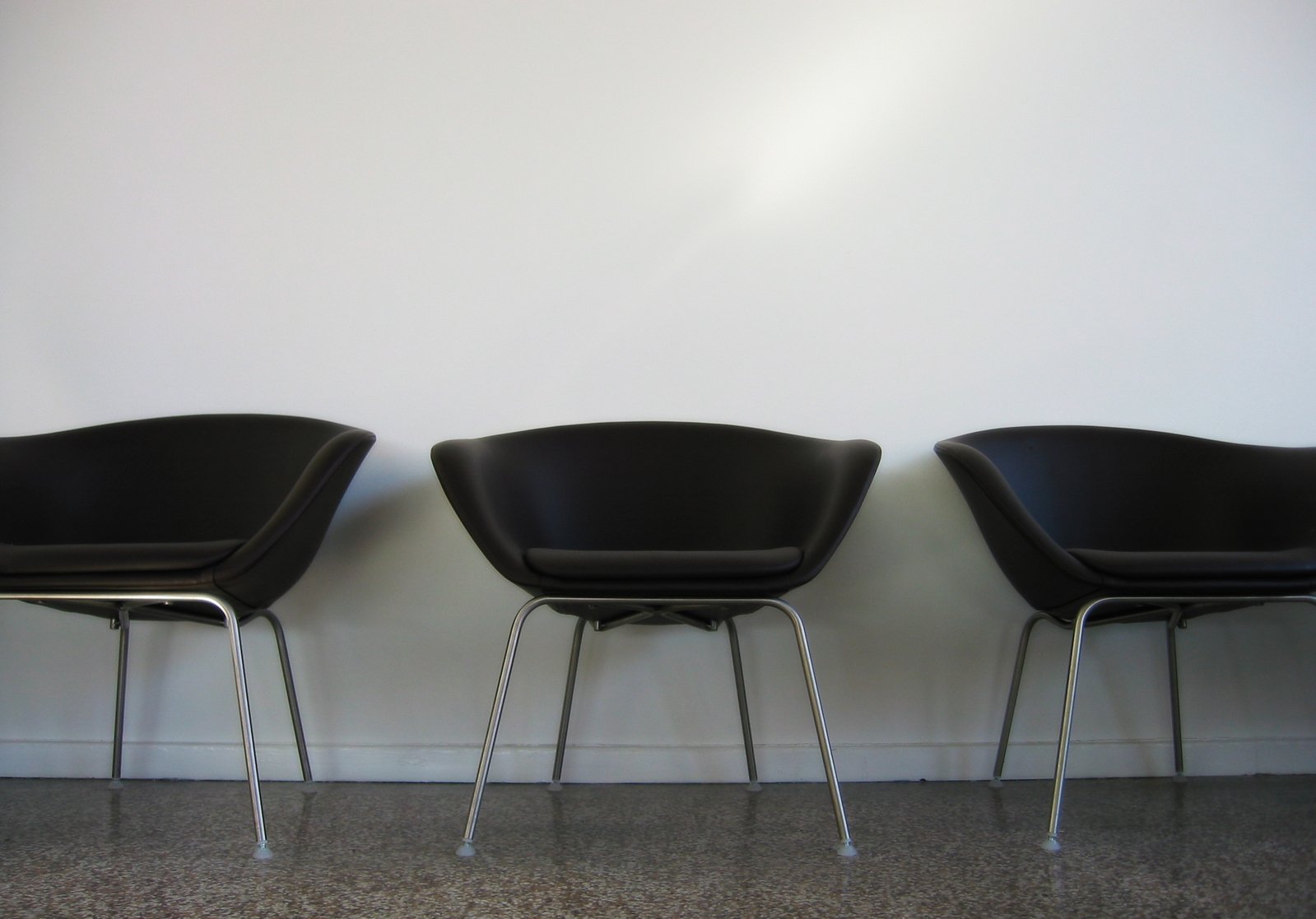 three chairs sitting side by side in front of a wall