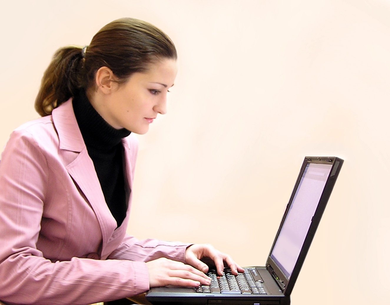 a woman in pink jacket working on laptop computer
