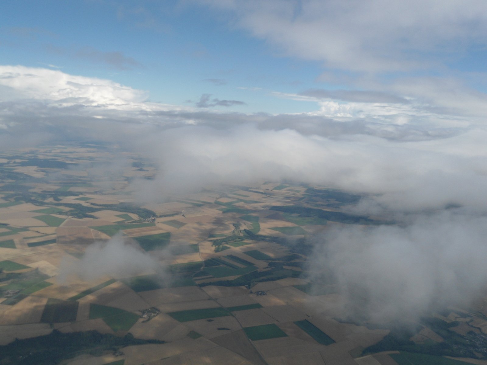 clouds rolling over farm land from an airplane