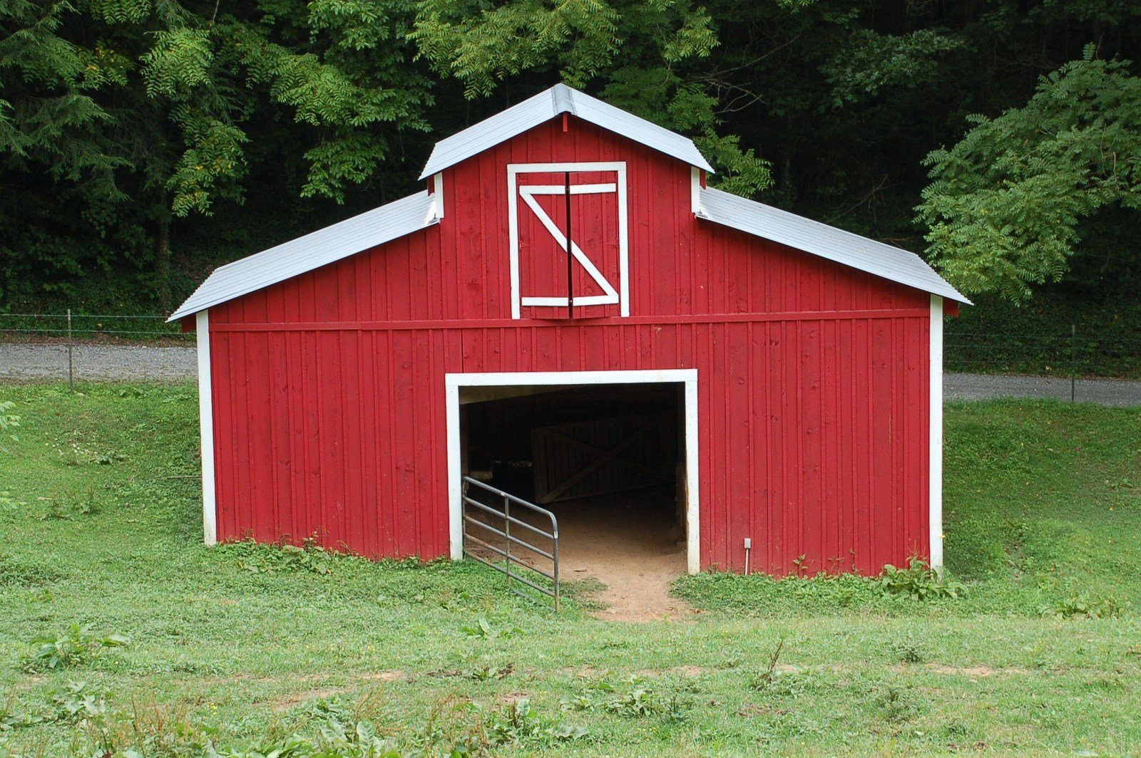 a large barn with the door open in a field