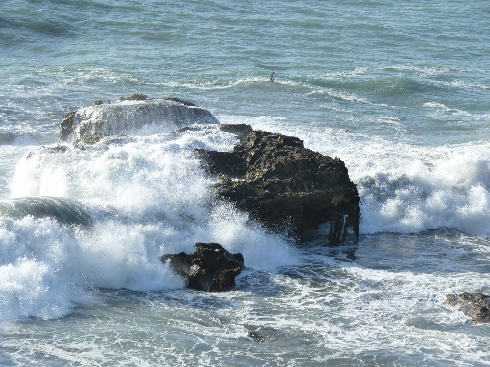 the water is rushing about a rocky shore