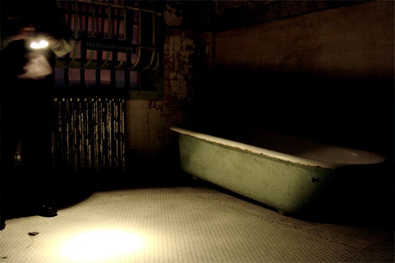 light shines on an old fashioned bathtub in an old building
