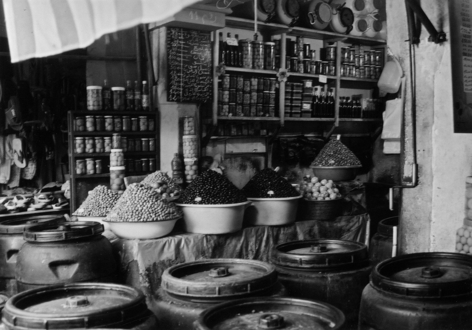 a market area filled with lots of barrels and buckets of food