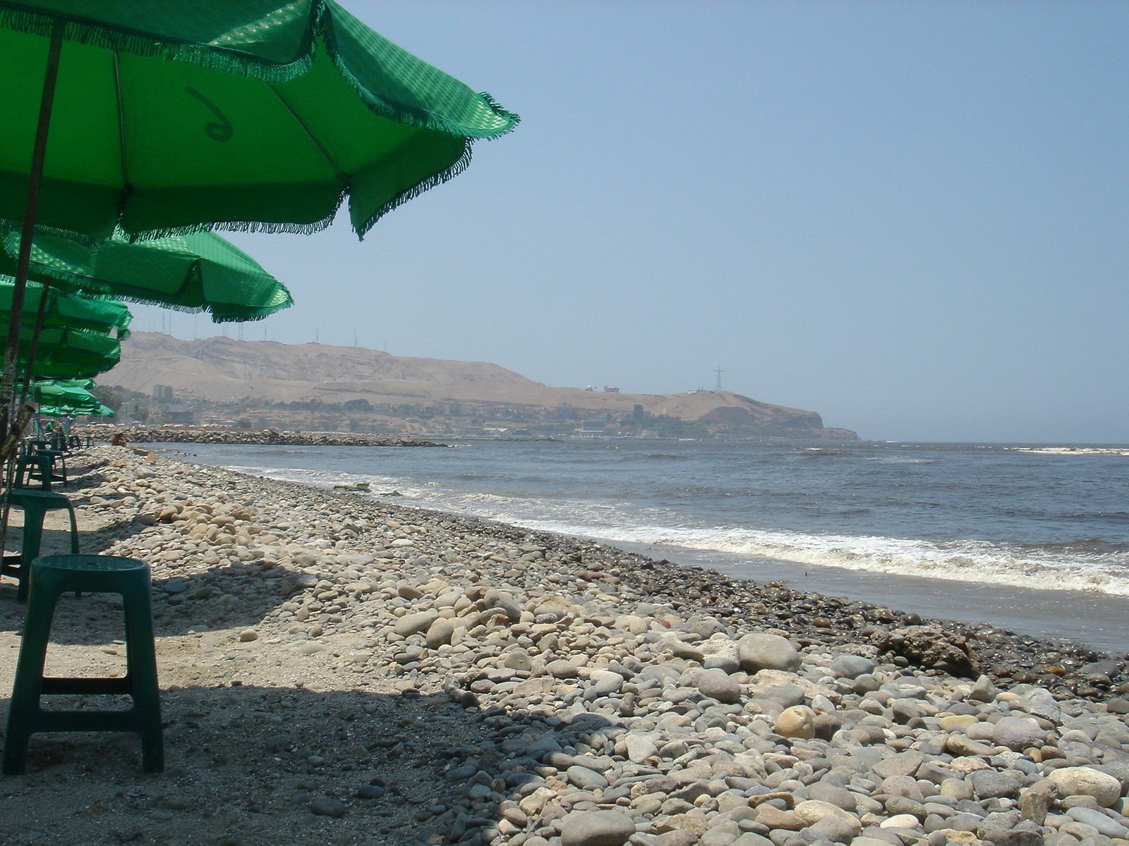 a row of green beach chairs next to the ocean