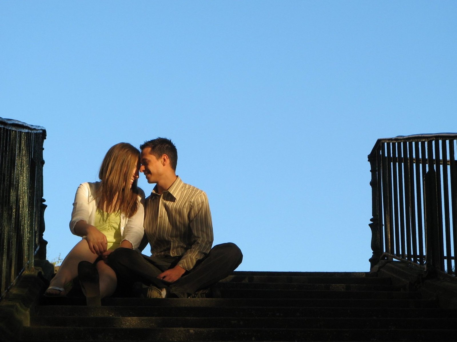 a couple sitting on a balcony kissing at sunset