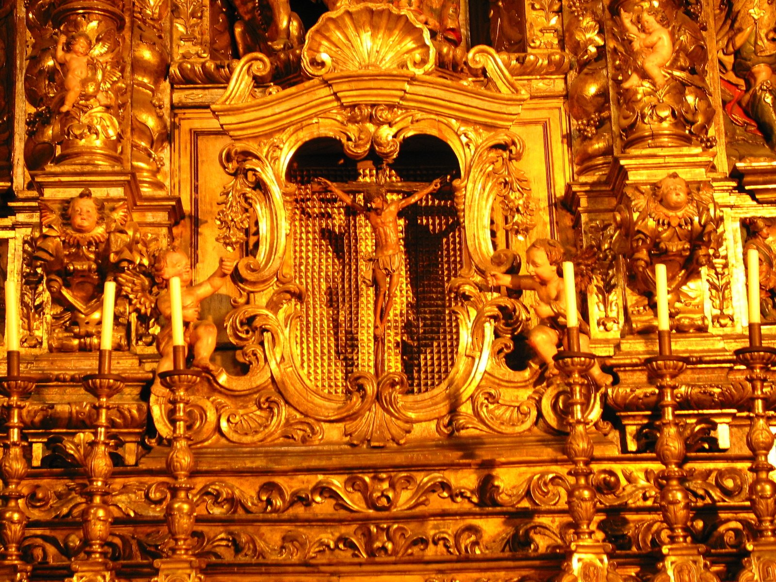 a clock with ornate decorations around it sitting next to candles