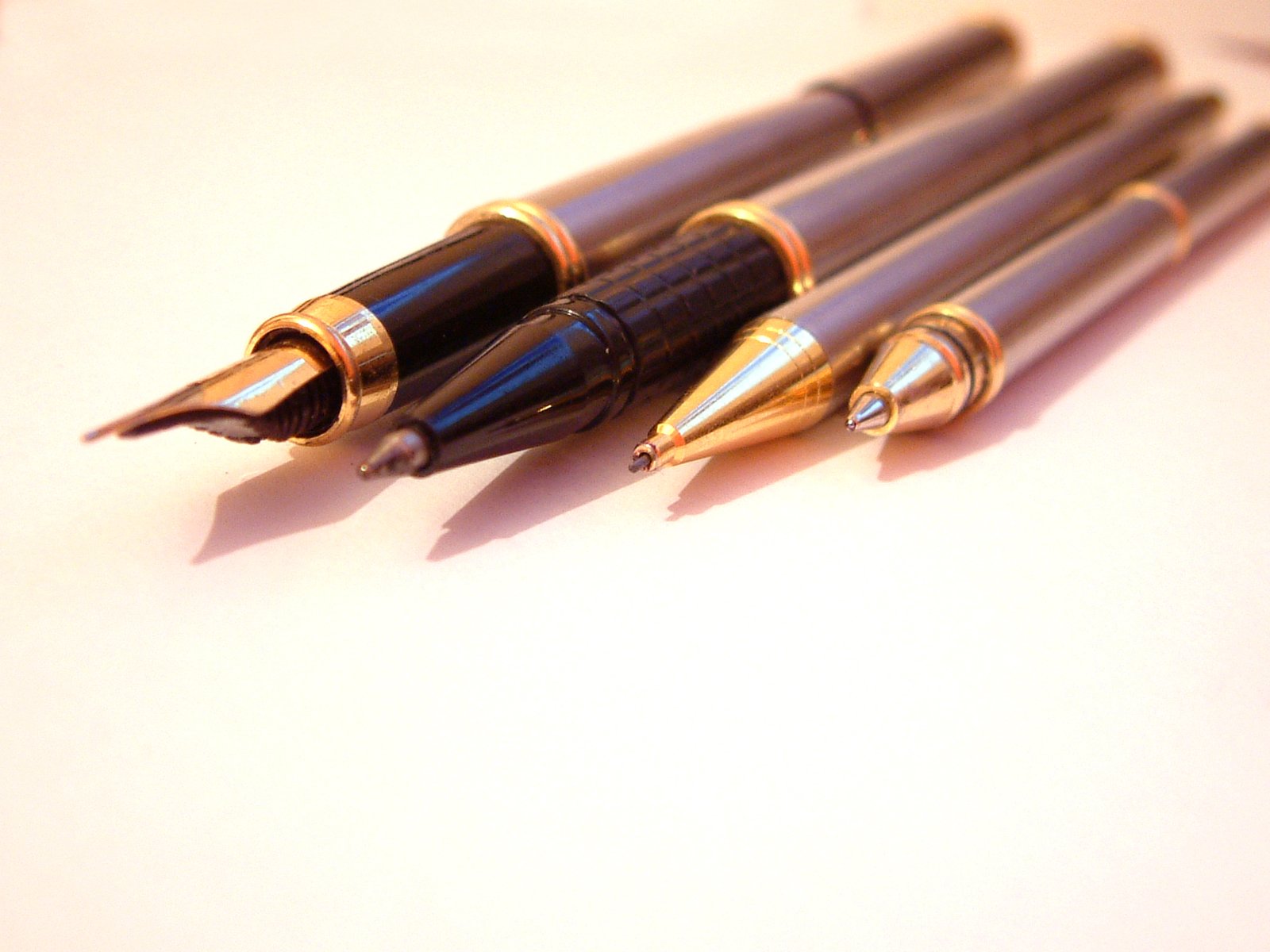 five fountain pens lined up on a desk