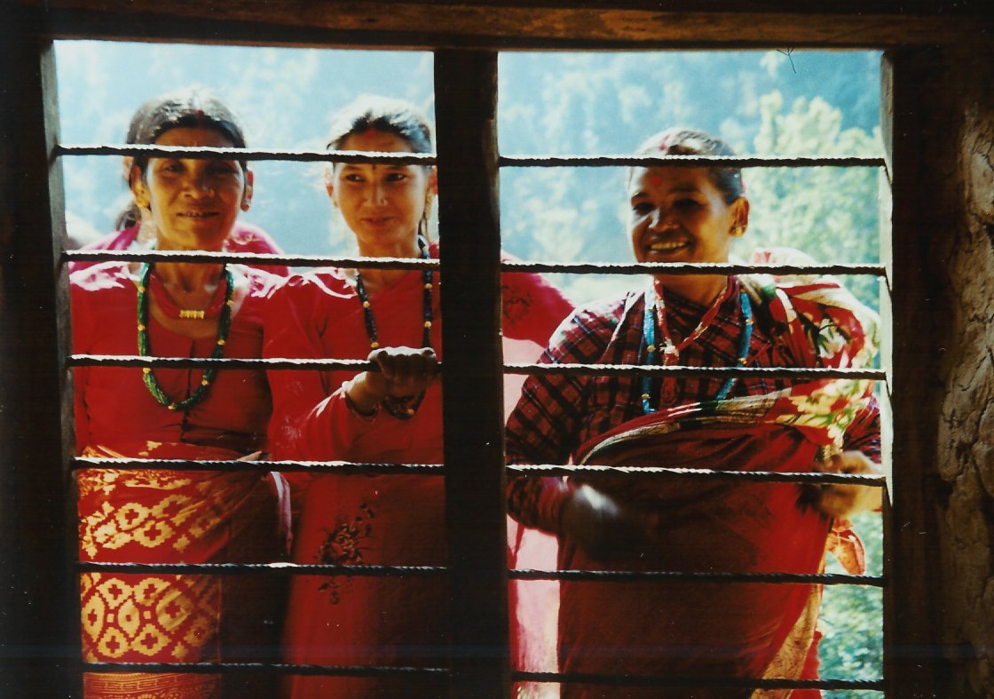 three people standing behind bars in front of a window