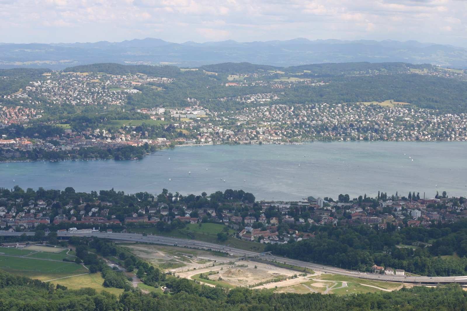 a wide view of a town, with a body of water and mountains in the distance