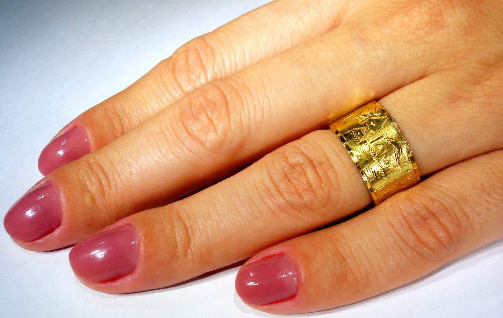 a person wearing a gold band that has a ring on it