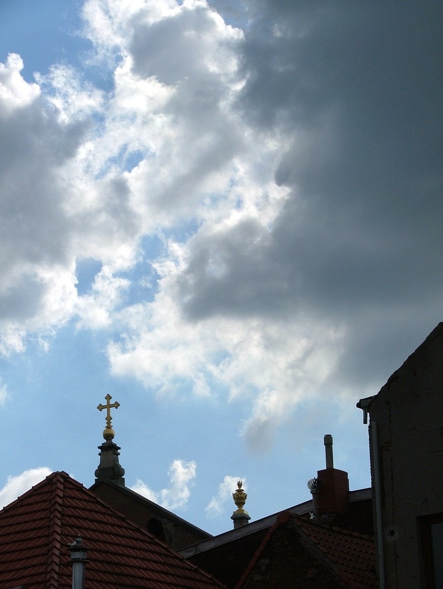 looking up at the clouds, roofs and crucifix on a sunny day