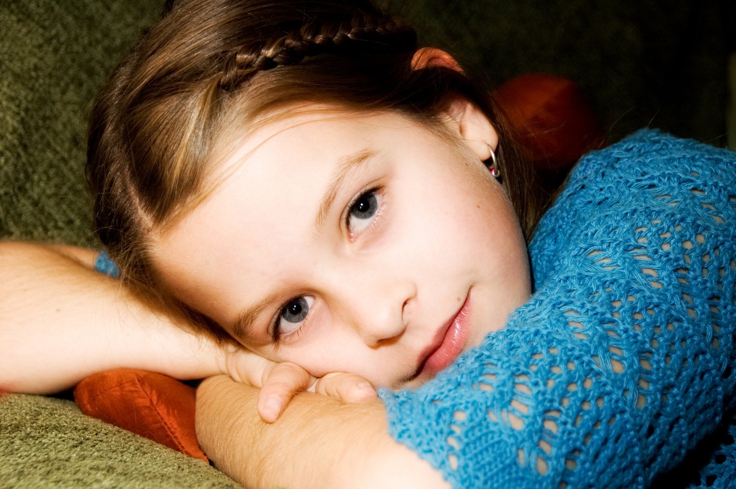 a girl is laying on a green couch with her arm wrapped up