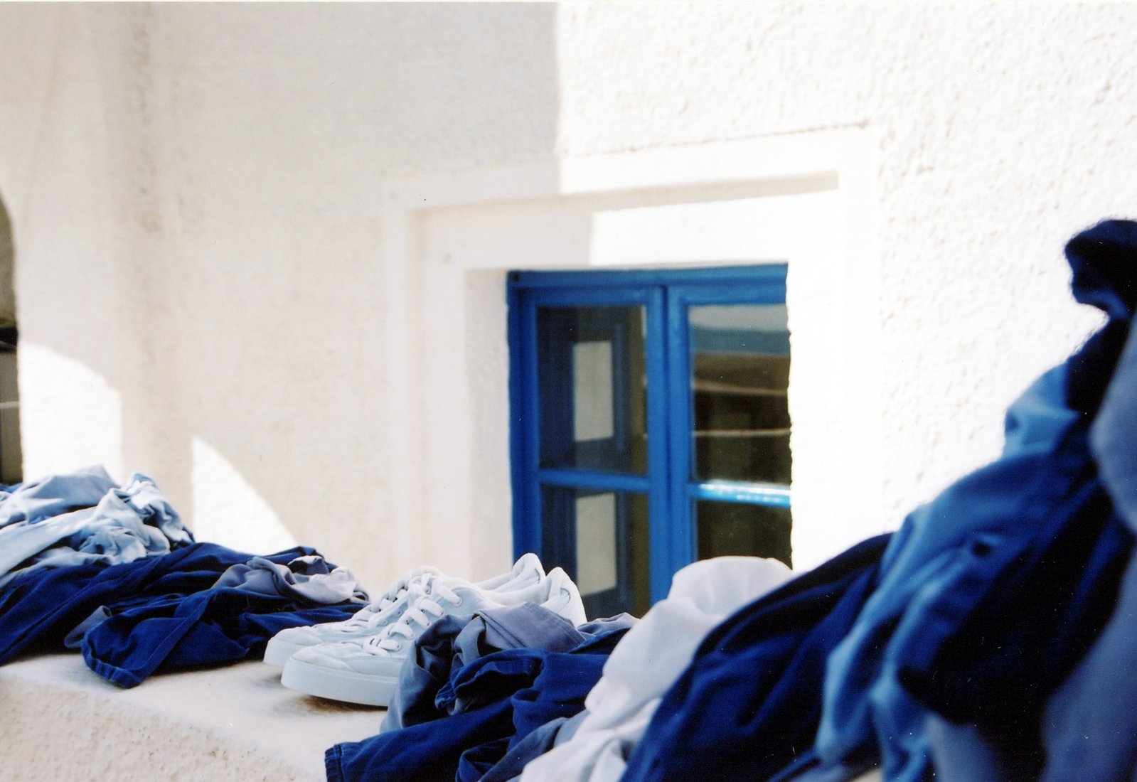 folded shirts lined up on a ledge with a blue door behind them