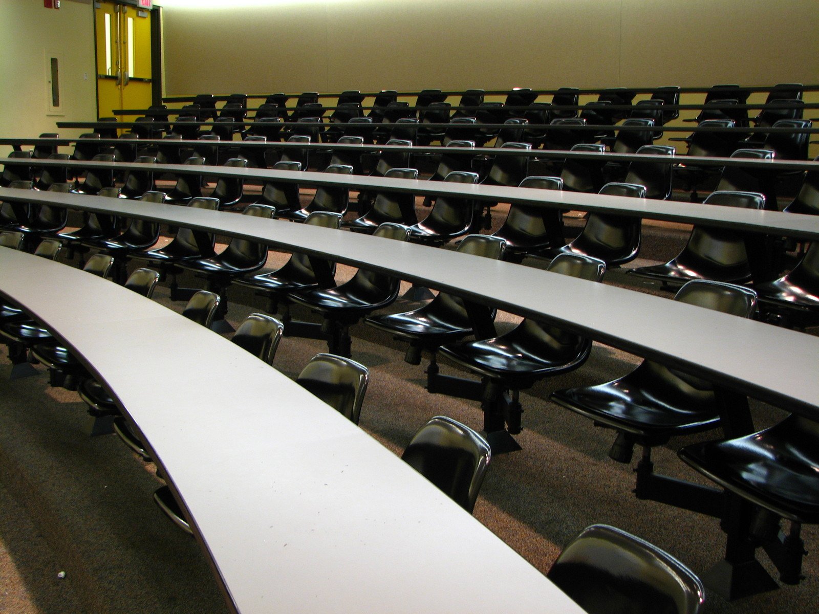 an empty meeting room with rows of white desks